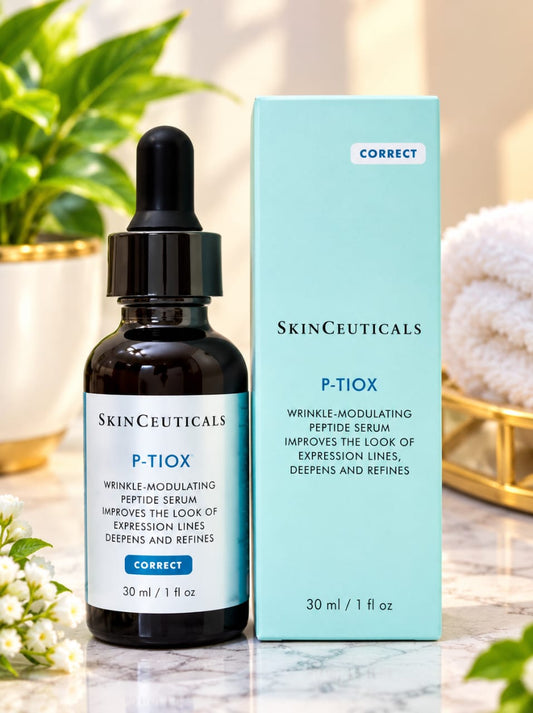SkinCeuticals P-Tiox serum bottle next to its light blue packaging box, displayed on a marble surface with a soft, blurred background of green plants and a towel.